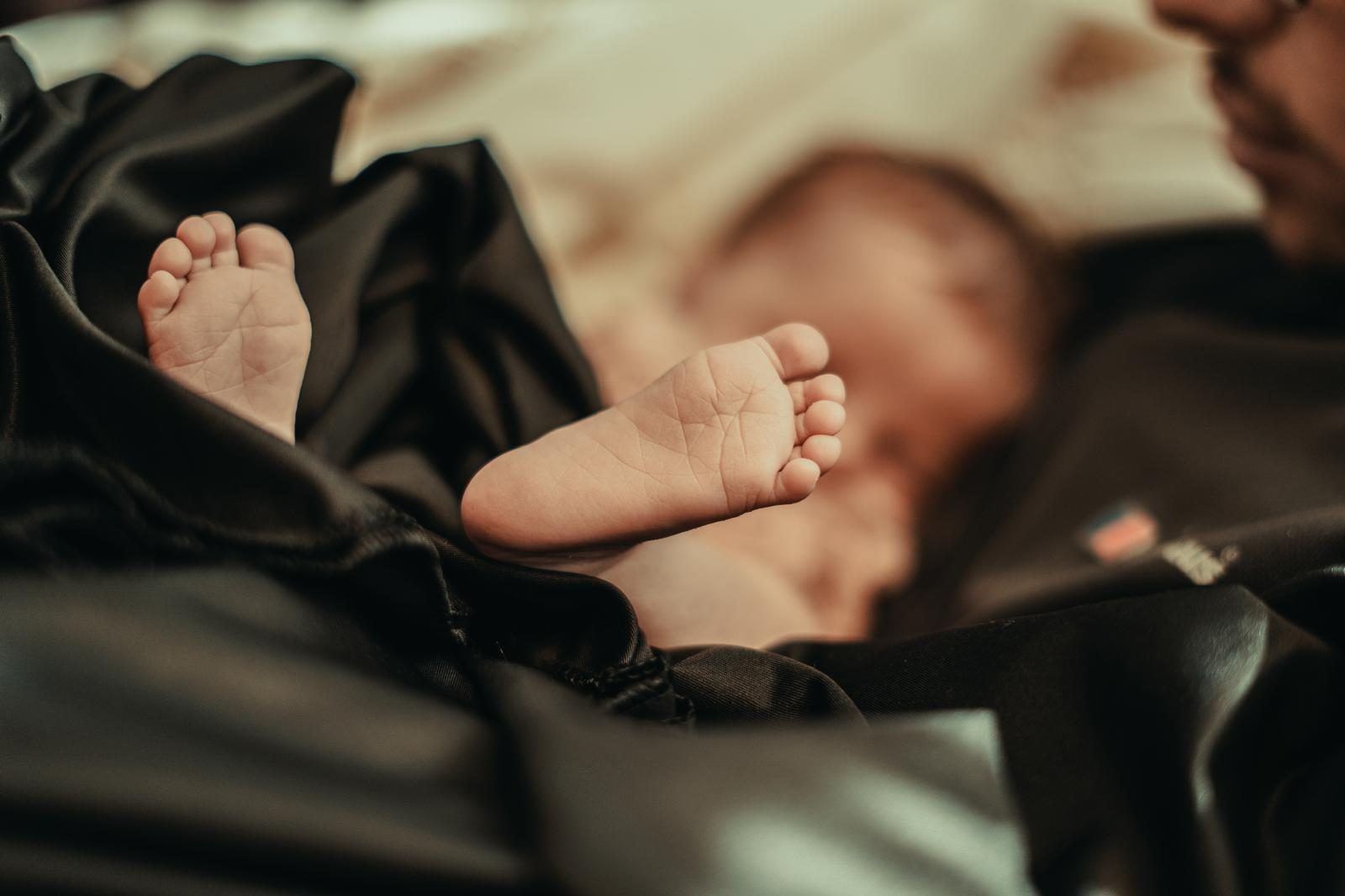 Newborn feet held by parent, warm tones