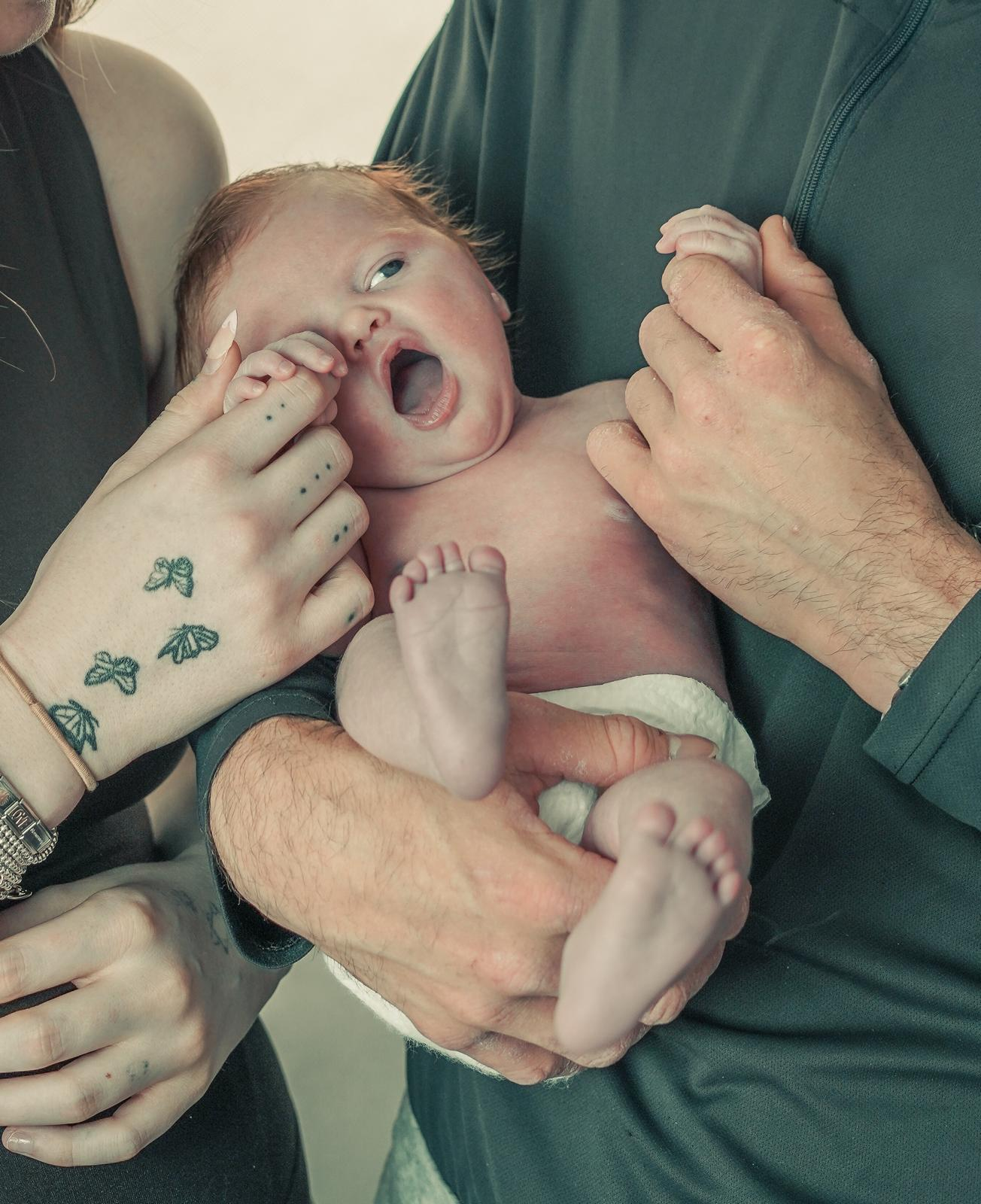 Parents holding newborn, candid moment
